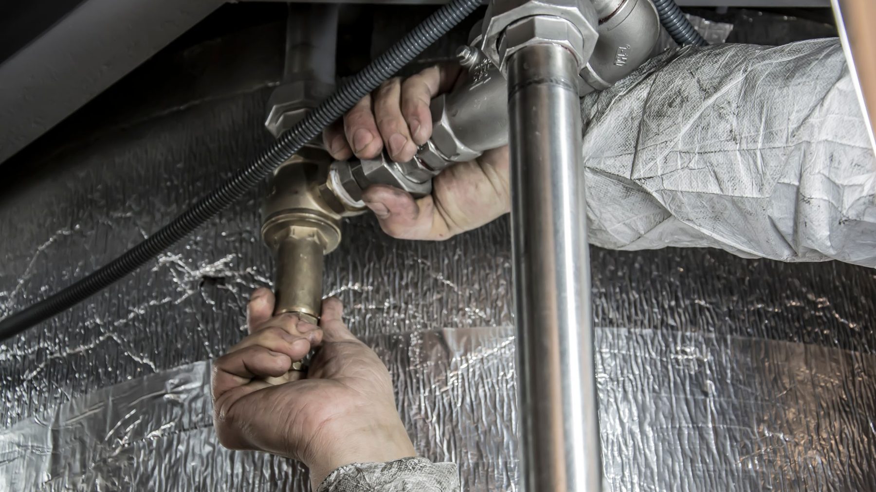 Hands working on a pipe fitting.